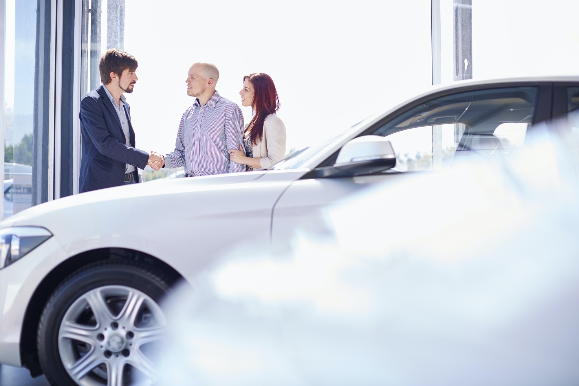 Car dealer with couple in showroom